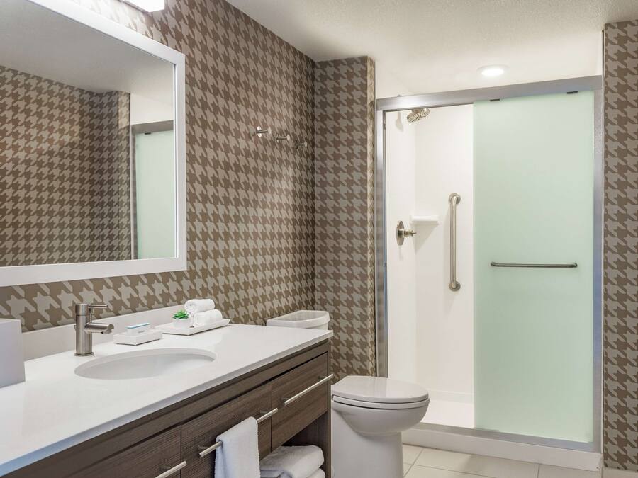 A bathroom with a large mirror, a sink, a toilet, and a shower.
