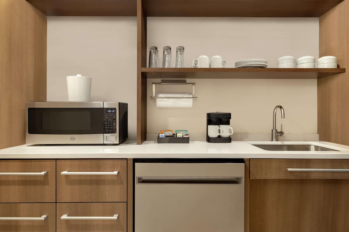 A modern kitchen with a microwave, coffee maker, and sink.