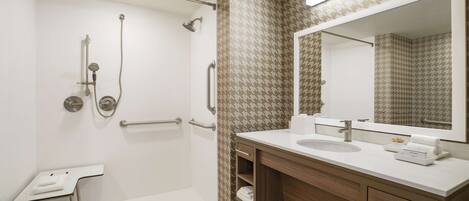 A modern bathroom with a walk-in shower, a sink with a mirror, and a vanity with drawers.