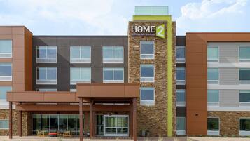 A modern hotel with a prominent 'HOME 2' sign, large windows, and a covered entrance area.