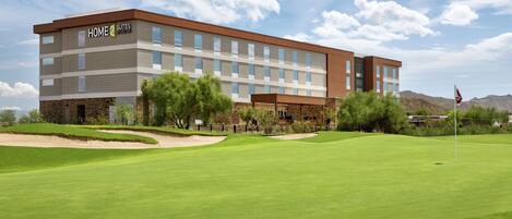 Et moderne hotel med flad tag, mange vinduer og et skilt der viser "HOME 2 SUITES SYDNEY".