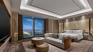 A modern hotel room with a large bed, a sofa, a TV, and a city view. - DoubleTree by Hilton Qidong, China (Nantong)