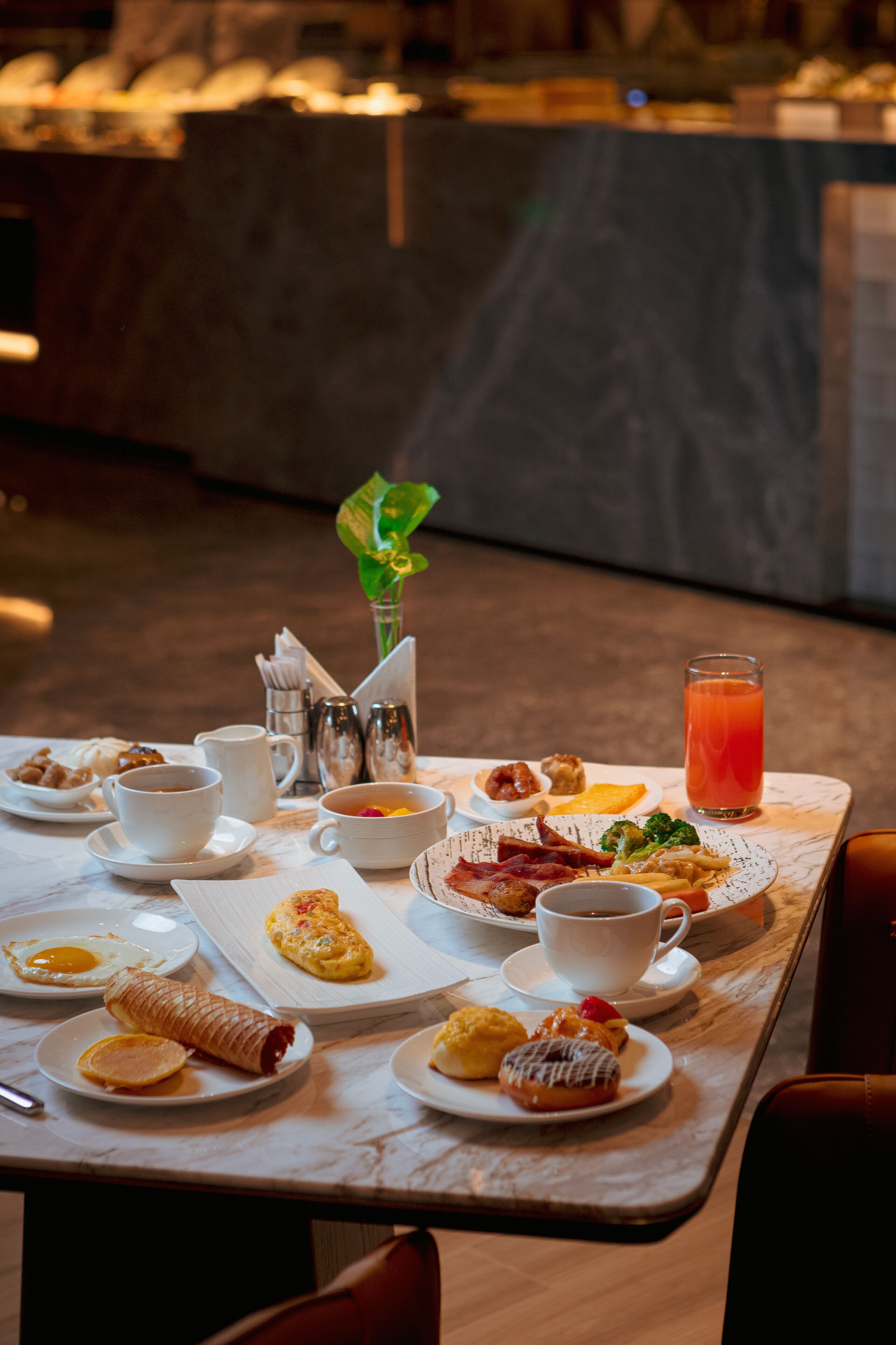 A breakfast table with various dishes, including eggs, pastries, and a glass of juice.