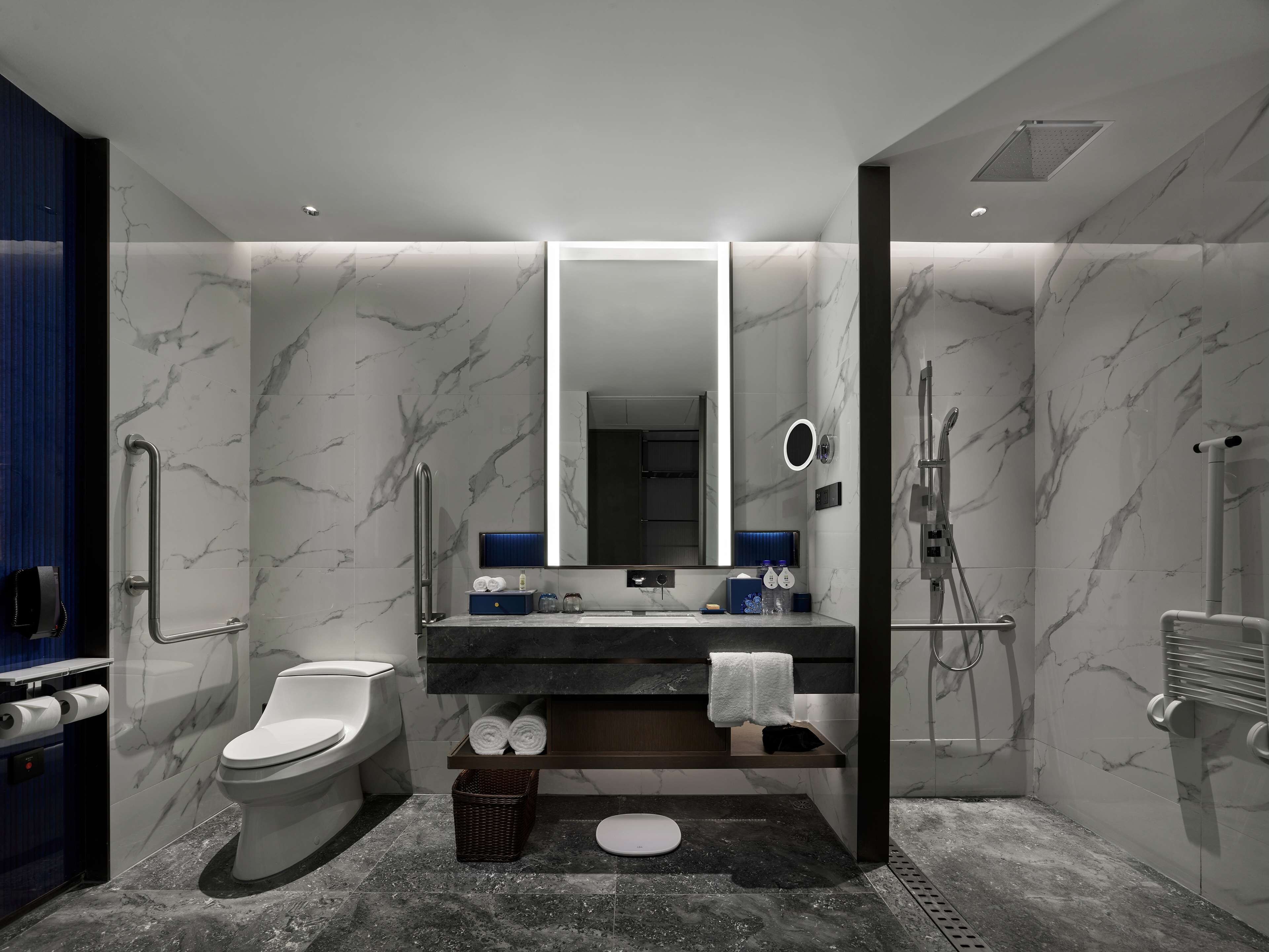 Et moderne badeværelse med toilet, håndvask, spejl og bruser.