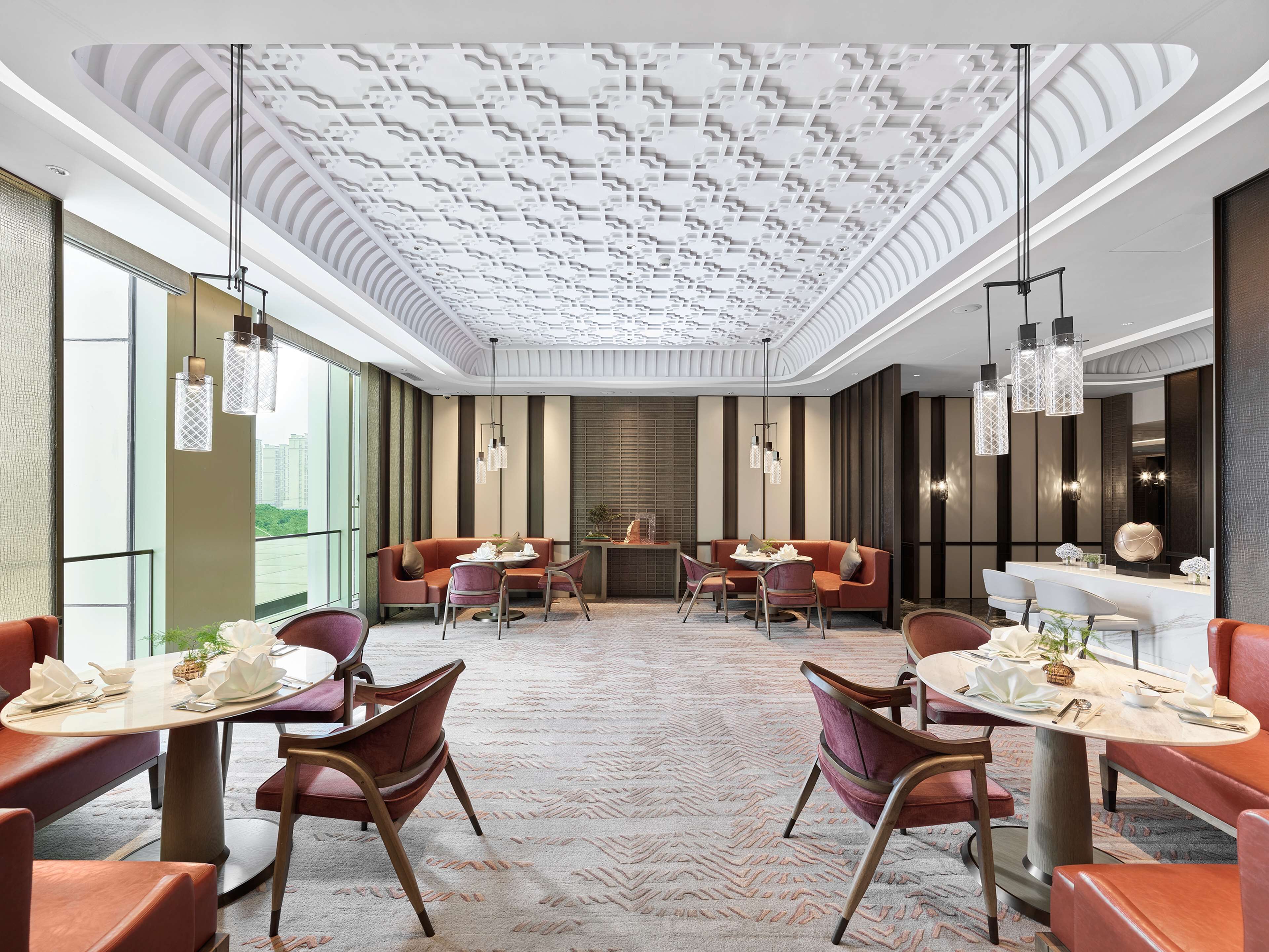Un moderno vestíbulo de hotel con techo alto y diseño decorativo, además de zonas de estar.