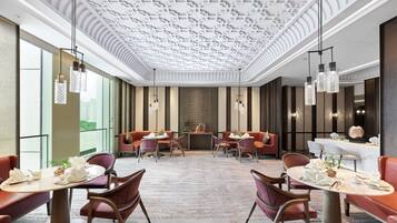 Un moderno vestíbulo de hotel con techo alto y diseño decorativo, además de zonas de estar.
