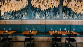 A restaurant interior with wooden tables, black chairs, and a wall decorated with hanging light fixtures.
