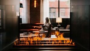 A modern interior with a fireplace, seating area, and large windows. - Canopy by Hilton Portland Waterfront (Portland)