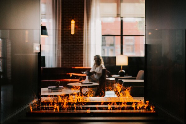 A modern interior with a fireplace, seating area, and large windows.