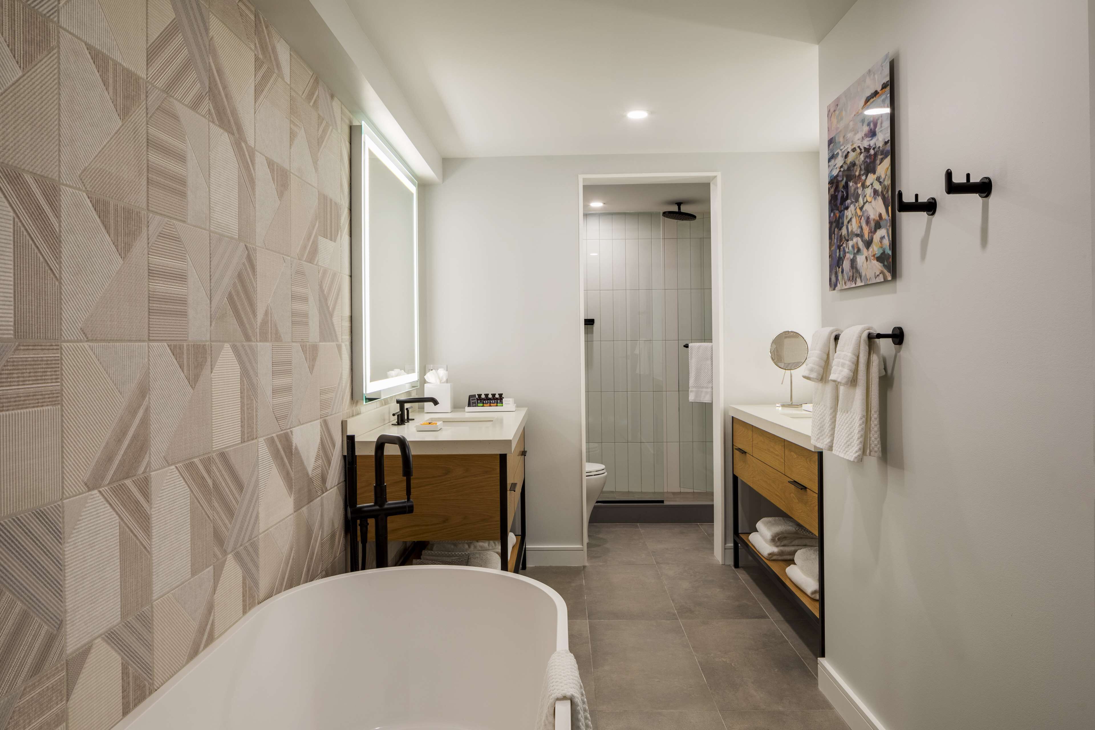 A modern bathroom with a freestanding bathtub, a vanity with a mirror, and a shower area.