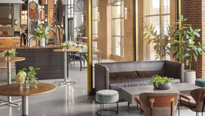 A modern interior with wooden panel ceilings, a central seating area with sofas and tables, and a variety of decorative mirrors. - Canopy by Hilton Portland Waterfront (Portland)