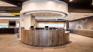 Una moderna zona de recepción de hotel con un mostrador circular, múltiples monitores de ordenador y un televisor de pantalla plana grande.
