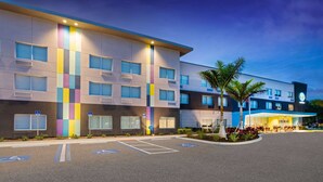 Un hotel moderno con una estructura de varios pisos, amplias ventanas y un estacionamiento con acceso para personas con movilidad reducida.