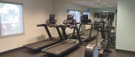 A gym with treadmills, elliptical machines, and a stationary bike.