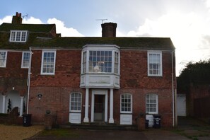 A two-story brick building with a bay window, white doors, and a small porch. - Whitefriars (Rye)