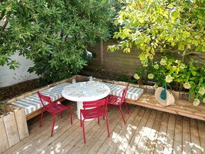 Un área de comedor al aire libre con una mesa redonda, sillas rojas y un banco.