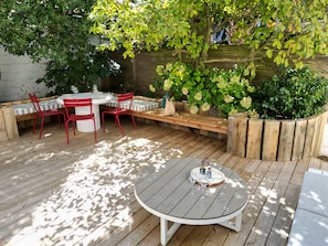 A wooden deck with a round table and red chairs, surrounded by greenery and a wooden fence. - COCOON • KEYWEEK Holiday House with lovely patio in Biarritz city center (Biarritz)