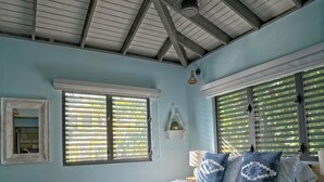 Ein Schlafzimmer mit einem Bett, Holzboden und einem Deckenventilator.