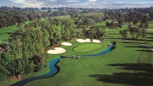 Un parcours de golf avec des bunkers de sable, un obstacle d’eau et un pont.