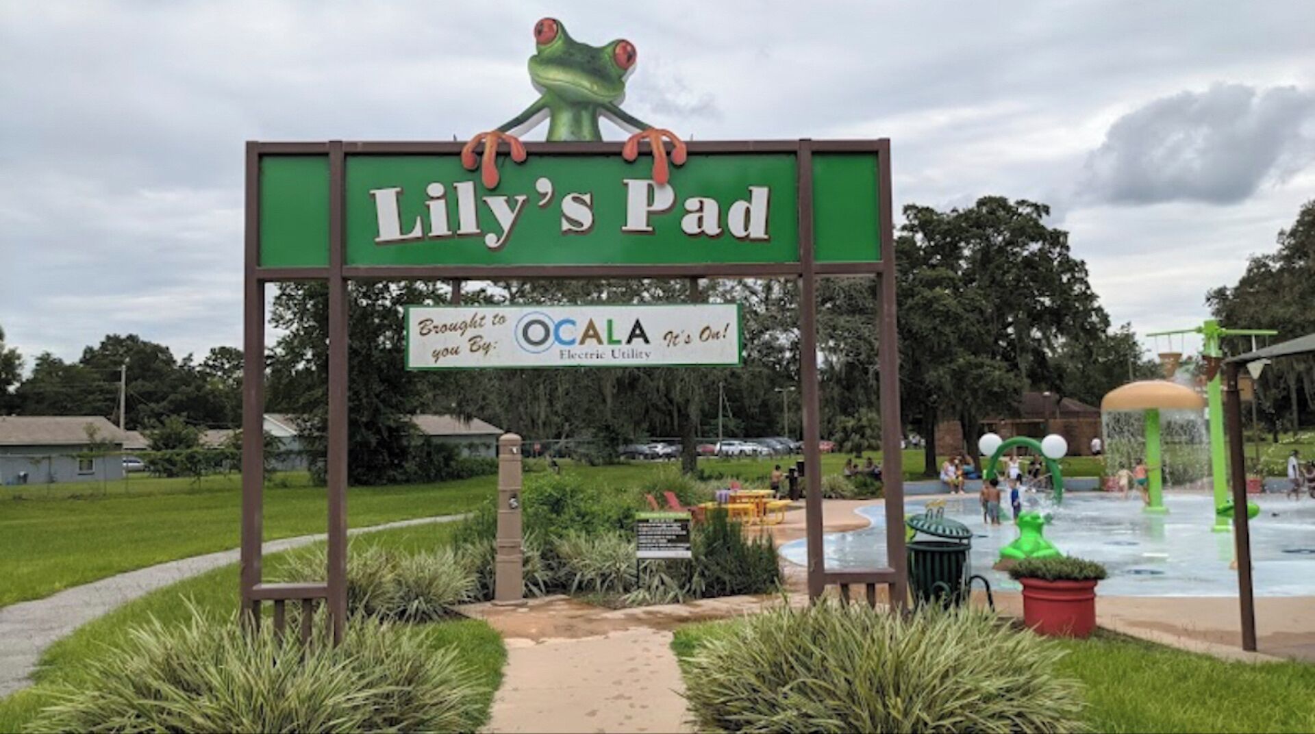 Schild für Lily's Pad mit Froschmaskottchen, einem Wasserpark und einem Weg dorthin.