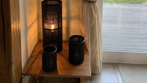 Een houten bank met twee zwarte kandelaars en een spiegel aan de muur.
