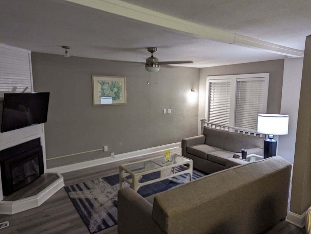 A living room with a fireplace, sofa, coffee table, and a ceiling fan.