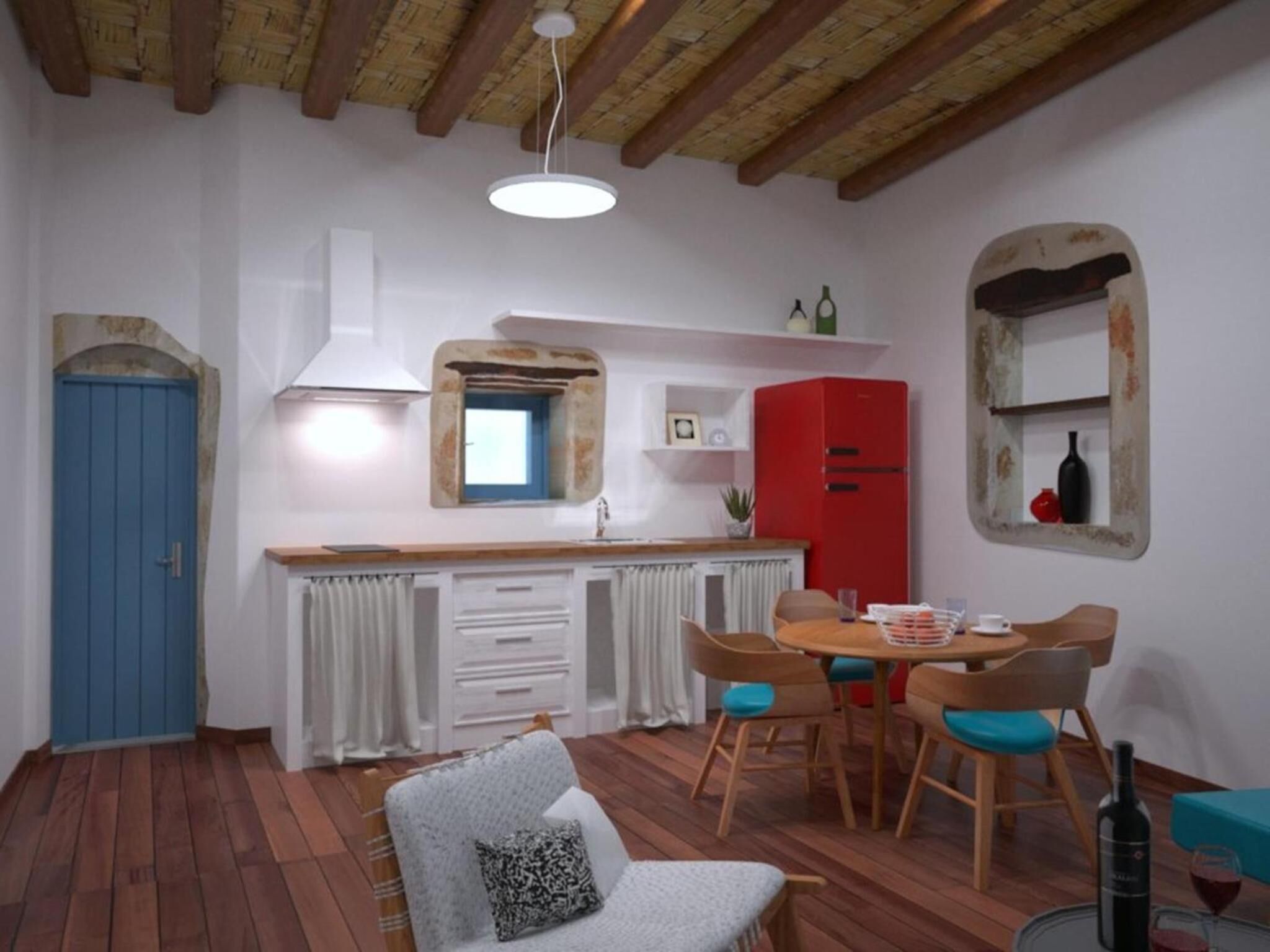 A compact kitchen with a blue door, a red refrigerator, and a dining area with wooden chairs and a table.