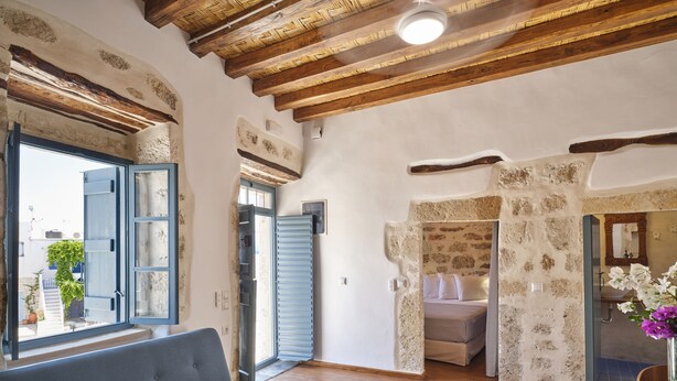 A cozy room with a blue sofa, wooden flooring, and a stone wall.