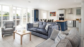 A modern living room with a grey sofa, a patterned armchair, and a wooden coffee table. - Hot Tub Haven, sleeps 8 in rural scenic Northumberland (Chatton)