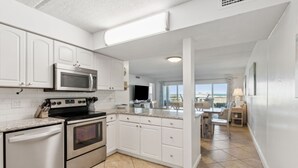 A modern kitchen with white cabinets, stainless steel appliances, and a large island. - Direct Pool and Oceanfront Views | Ground Level Amelia By The Sea | Exclusive Access to the Pier (Fernandina Beach)