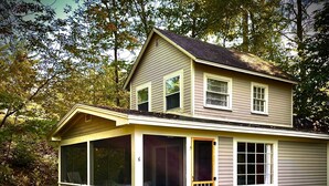 Une maison à deux étages avec un porche à l’avant, de grandes fenêtres et une porte.