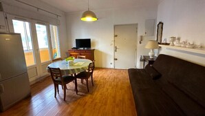 Un espacio habitable compacto con una mesa de comedor, sillas, un sofá, un televisor y una lámpara.