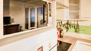 Una cocina con microondas, armarios y una ventana.