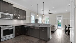 Une cuisine moderne avec des meubles de couleur sombre, des appareils électroménagers en acier inoxydable et un grand îlot central.