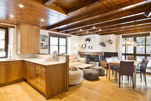 Una cocina amplia con armarios de madera, un comedor con mesa y sillas, y una chimenea.