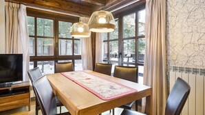 Un coin repas avec une table en bois, six chaises et deux lampes suspendues.