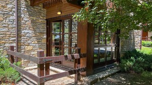 Un bâtiment rustique en pierre, doté d’un porche en bois et d’un portail en métal.