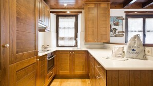 Une cuisine avec des meubles de rangement en bois, un plan de travail blanc et une fenêtre donnant sur l’extérieur.