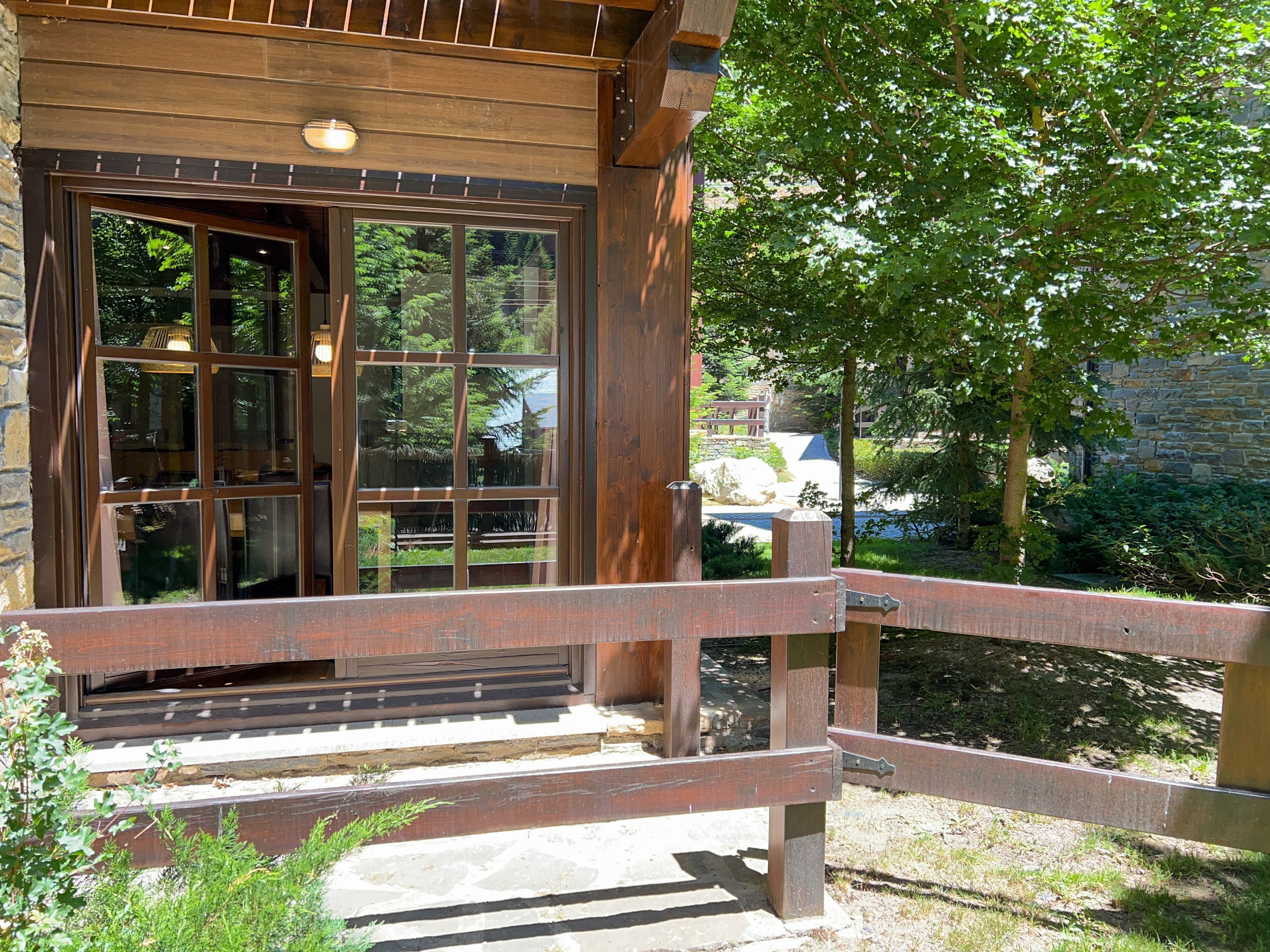 A wooden cabin with a large window and a wooden porch.