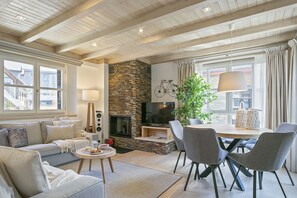 A modern living room with a fireplace, a dining area, and a sofa set.