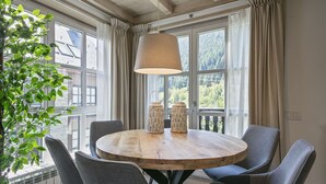 Un tavolo rotondo in legno con quattro sedie, un lampadario e due portacandele intrecciati.