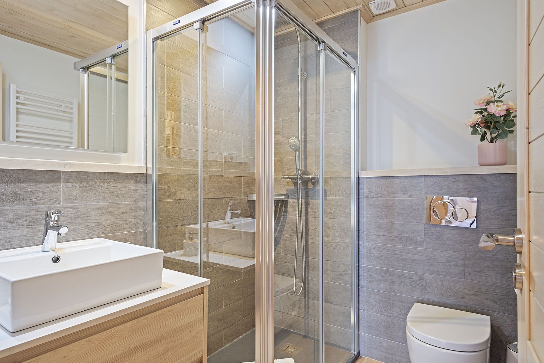 A modern bathroom with a glass-enclosed shower, a white sink, and a toilet.