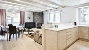 Een moderne woonkamer met een eethoek, een kookeiland en een stenen openhaard.