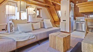 Een knus loft-achtig vertrek met een bank, houten salontafel en hanglampen.