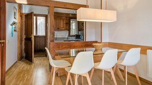 A modern kitchen with wooden cabinets, a glass dining table, and white chairs.