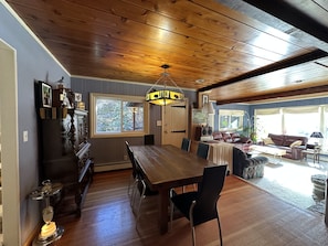 A spacious dining area with a wooden table and chairs, a chandelier, and a view of the outdoors through a large window. - Streamside dream with hot tub (Idaho Springs)