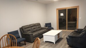A living room with a grey sofa, a white coffee table, and a wooden dining table with chairs. - Cardinal Crest of Sister Bay (Sister Bay)