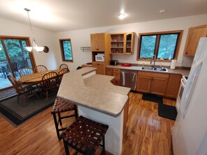 A modern kitchen with wooden cabinets, a stainless steel dishwasher, and a large island. - Cardinal Crest of Sister Bay (Sister Bay)