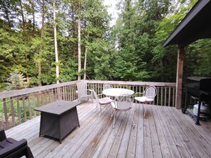 A wooden deck with a table and chairs, surrounded by trees. - Cardinal Crest of Sister Bay (Sister Bay)