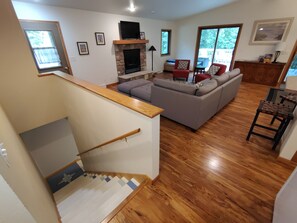 A spacious living area with a staircase, a fireplace, and a large window. - Cardinal Crest of Sister Bay (Sister Bay)